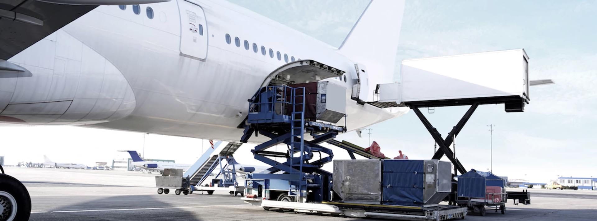 Avión de carga con bodega abierta y equipos de carga en pista — logística aérea de alta exigencia